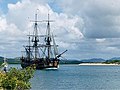 A three-masted sailing ship crossing a bay