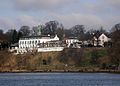 Südost-Ansicht des Hotelrestaurants Jacob von der Elbe aus. Am Ufer bildet der Elbuferweg einen kurzen Abschnitt des Elbuferwanderweges, der hier vorbeiführt. Rechts ist die Jacobs Treppe zu erkennen, die hier von der Höhe der Elbchaussee hinunter zum Ufer führt. Bei dieser Treppe erinnert ein Gedenkstein an die Primus.