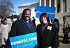 A photograph of a group of people holding placards with "saveROE.com" on them