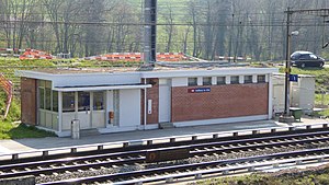 Boxy single-story building on platform next to double-tracked railway line