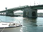 An aging concrete and steel bridge crossing calm waters on a sunny day