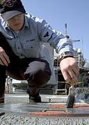 US Navy 080909-N-0483B-005 Sonar Technician (Surface) 3rd Class James Garringer, from Bridgeville, Ind., paints a hatch on the fantail of the guided-missile cruiser USS Shiloh (CG 63).jpg