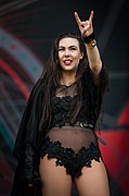 Elize Ryd en habits noirs levant sa main gauche en faisant le signe des cornes