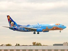 An advertisement for the film on a WestJet Boeing 737-8CT at John F. Kennedy International Airport depicting Elsa showcasing her power and Olaf enjoying the summer