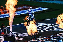 Stunt performer Robbie Knievel jumping at the Texas Motor Speedway in 2008 as part of a promotion. Three flames surround Knievel while he's performing.