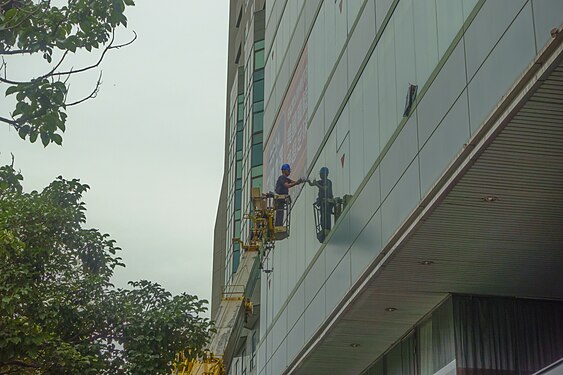 The worker was paste a new advertising banner on the glass surface of building window.