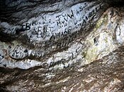 Lettres en noir sur le mur d'une grotte préhistorique.