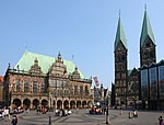 A dark stone gothic building in a paved town square.