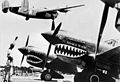 B-24 Liberator taking off above P-40 Warhawks