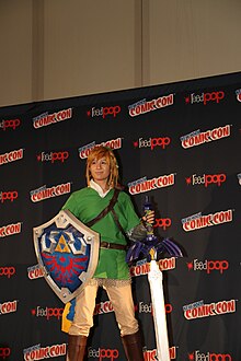 A cosplayer dressed as Link holding the Master Sword