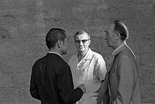 Photographie en noir et blanc de trois hommes en train de discuter.