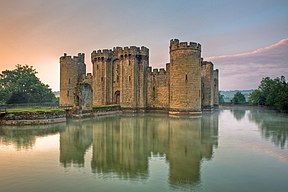 A castle of square plan surrounded by a water-filled moat. It has round corner towers and a forbidding appearance.