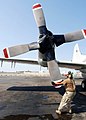 Airman rotates the propeller on an EP-3E Orion engine as part of preflight checks