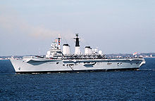 Side view of a small aircraft carrier with a ski-jump ramp underway