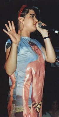 Zdjęcie z 1996 roku. Młoda kobieta zwrócona jest w stronę fotografa prawym bokiem. W lewej dłoni trzyma mikrofon, prawą zaś, na której widoczny jest pierścionek, unosi otwartą. Wokalistka ubrana jest w koszulkę z wizerunkiem półnagiego mężczyzny.