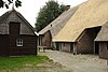 Boerderij met gewijzigde topgevel en zijbaander onder schilddak, houten schuur onder schilddak en stookhok