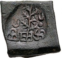 A coin of Takshashila, portrays a tree flanked by a hill surmounted by a crescent and a Nandipada above a சுவசுத்திக்கா.