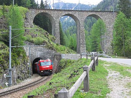 Strecke der Albulabahn zwischen Preda und Bergün. Der aus dem Toua-Tunnel auftauchende Zug hat knapp eine Minute zuvor den darüber liegenden Albulaviadukt III überquert