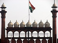The national flag of India hoisted on a wall adorned with domes and minarets