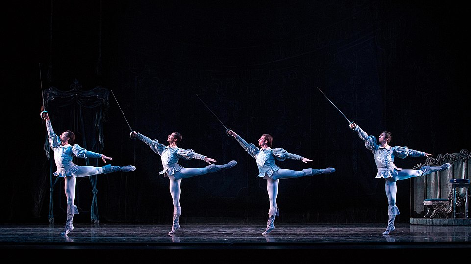 2015 年一場芭蕾舞表演； 四位男舞蹈員一齊做同步嘅 90 度第一阿拉伯斯卡。