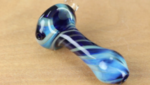 A small pipe made of blown blue glass on a wood table