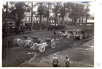 Photo noir et blanc de la place d'un village occupée par des fourgons.