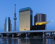 Asahi Breweries headquarters building with the Asahi Flame and Skytree at blue hour with full moon, Sumida-ku, Tokyo, Japan.