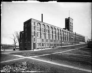 View of the Lafayette Avenue façade, looking east. In this 1911 photo, the building has only its original three stories, making the mid-block tower twice as tall as the rest of the building. Sidewalks and fire hydrants are installed, but the streets are still unpaved.