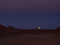 Salida de la luna sobre el camino de 12 m de ancho que conduce al Llano de Chajnantor.