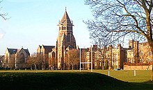 Una amplia toma de una antigua escuela inglesa con una torre central, con un campo de deportes en primer plano.