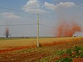 畑地で塵旋風が発生し赤土を巻き上げている