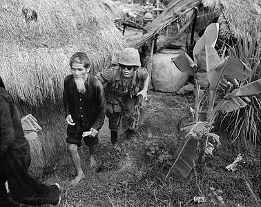 A United States Marine of the 1st Battalion, 3rd Marines moving a suspected Viet Cong, 15 miles west of Da Nang Air Base, 1965.