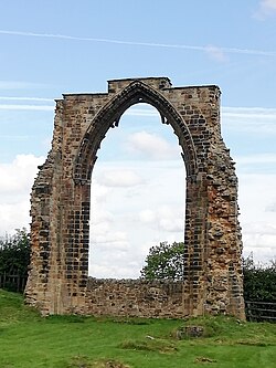 A photograph showing a Gothic arch standing in a field.