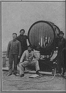 Photographie en noir et blanc de quatre hommes auteur d'un projecteur.