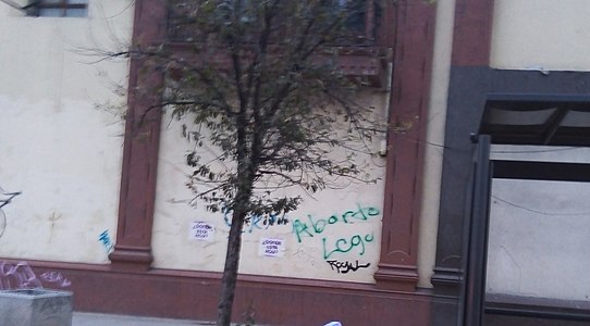 Graffitis kaj paperoj gluitaj sur muroj dum feminista protesto en Meksiko