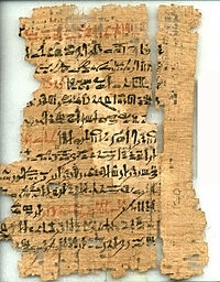 Стародавній, рваний і фрагментарний папірус, з рукописним почерком чорними і червоними чорнилами