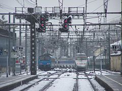 Un TER et un TGV quittent la gare sous la neige.