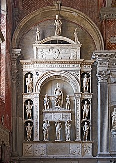 Image d'un monument funéraire où à l'intérieur d'une arcade flanquée de niches se trouvent six statues de jeunes guerriers en costume romain et trois figures viriles tenant le sarcophage du Doge, constitué d'un coffre à l'ancienne, couronné d'une cimaise arquée avec deux petits rinceaux sur les côtés. Le coffre est tripartite avec des bas-reliefs. Sur le sarcophage debout se trouvent les statues du doge avec son armure d'acier et deux pages. Au-dessus d'un tympan semi-circulaire se trouvent trois statues du Christ rédempteur entre deux chérubins. Le socle de base est décoré d'une frise d'armes et de deux bas-reliefs avec Hercule et le Lion de Némée et Hercule contre l'Hydre de Lerne.