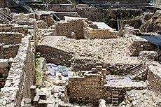 Looking down into a large excavation site, a glacis, seen in cross section, rests against a wall to the left