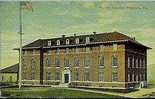 A color postcard showing a thee-and-a-half-story brick building with a pitched roof