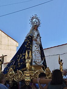 Procesión en la que se saca la imagen de la patrona del pueblo (Torres de la Alameda), la Virgen del Rosario por las calles. La virgen lleva un manto azul y va sobre unas andas que llevan algunos vecinos del pueblo.