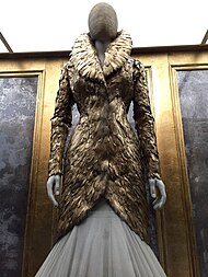 Dress that appears to be made of golden feathers, with high collar and long sleeves