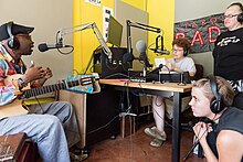 Un músico entrevistado nun estudo de radio por tres entrevistadores