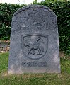 Historienstein mit dem Wappen der Abtei Stablo und der Jahreszahl 857, Basaltlava, 2016, von Karl-Rudolf Müller, neben dem alten Kirchenschiff