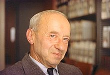 Balding man, with bookshelf in background