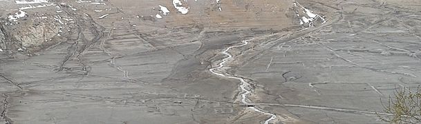 Vue de la route avec un petit pont et des traces d'habitations.