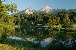 A lake flanked by trees and two mountains