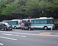 Dos Isuzu Erga Mio Autobuses en frente de Yasukuni Shrine con un Uyoku camión de ruido (Gaisensha) pasando por delante