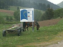 photographie couleurs : charrette à cheval derrière un panneau au logo européen