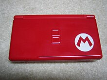 Nintendo DS Lite rosso con l'emblema di Mario (una M rossa racchiusa in un cerchio bianco) in basso a destra.